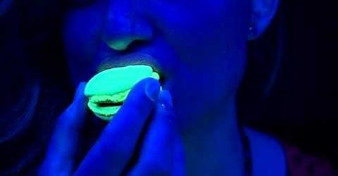 A glowing Luma Bites creation held under ultraviolet light